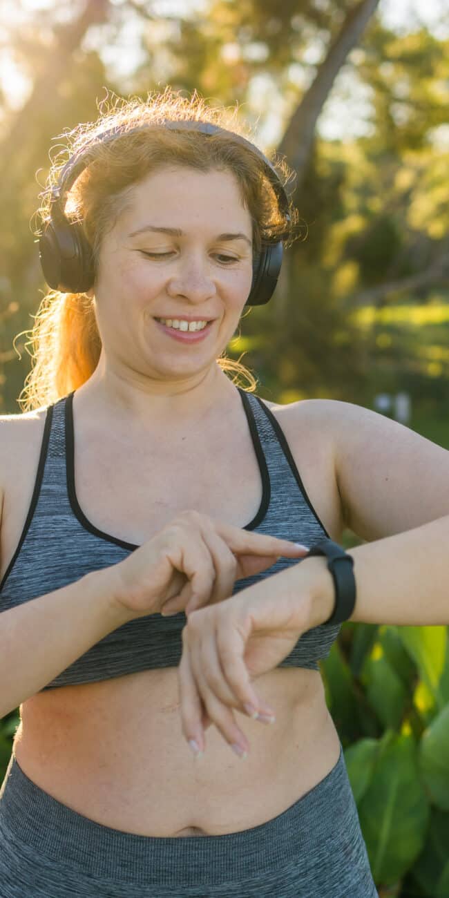 Fat woman checking time or heart rate from smart watch. Exercise or running outdoors for weight loss